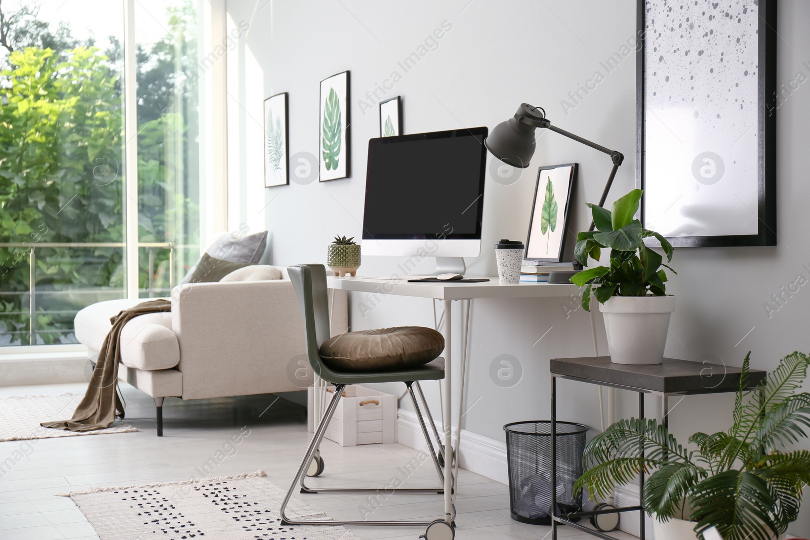 Photo of Comfortable workplace with modern computer and houseplants in room. Interior design