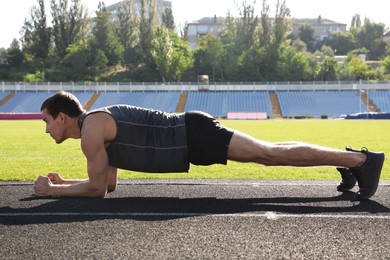 Sporty man doing plank exercise at stadium