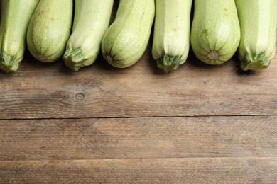 Photo of Raw green zucchinis on wooden table, above view. Space for text