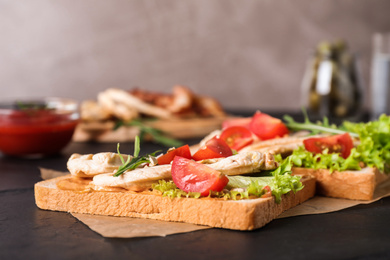 Photo of Delicious sandwiches with chicken on black table