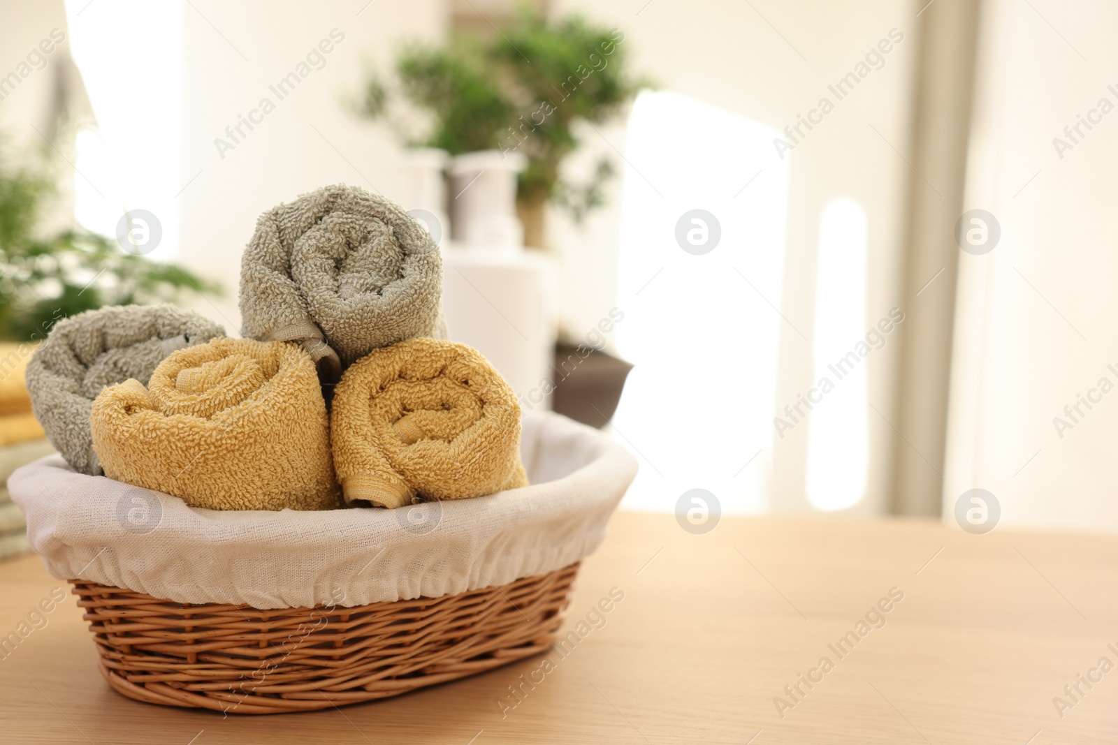 Photo of Basket with towels on wooden table indoors, space for text. Spa time