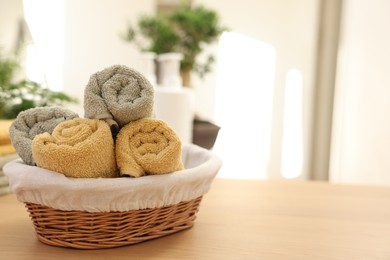 Photo of Basket with towels on wooden table indoors, space for text. Spa time