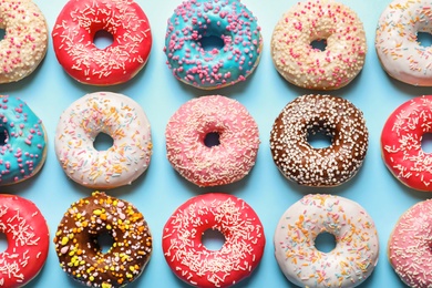 Delicious glazed doughnuts on color background, top view