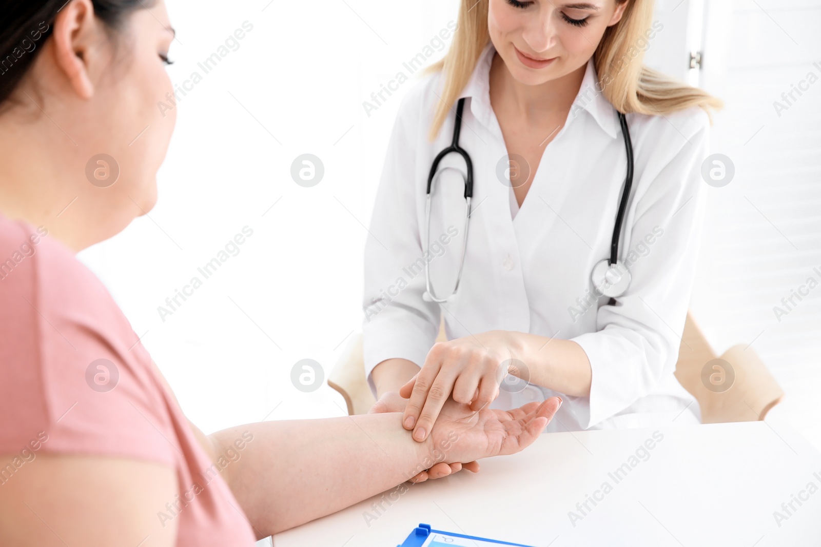 Photo of Female doctor taking pulse of overweight woman in clinic