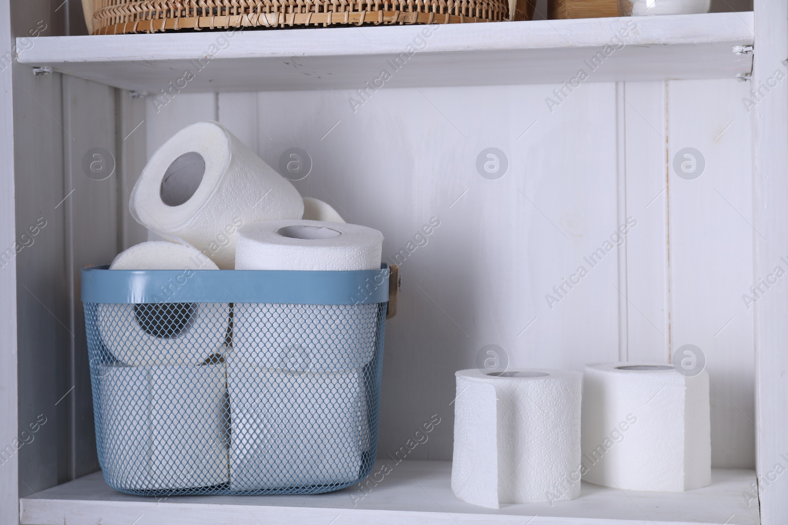 Photo of Toilet paper rolls in basket on white shelf