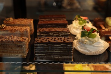 Photo of Different tasty desserts on counter in bakery shop, closeup