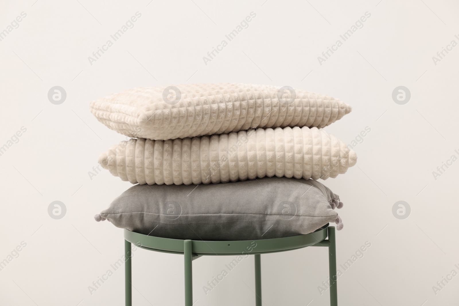 Photo of Soft pillows on side table near beige wall
