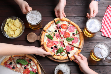 Photo of Friends with delicious pizza Diablo and beer at wooden table, top view