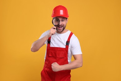 Emotional builder looking through magnifier glass on yellow background