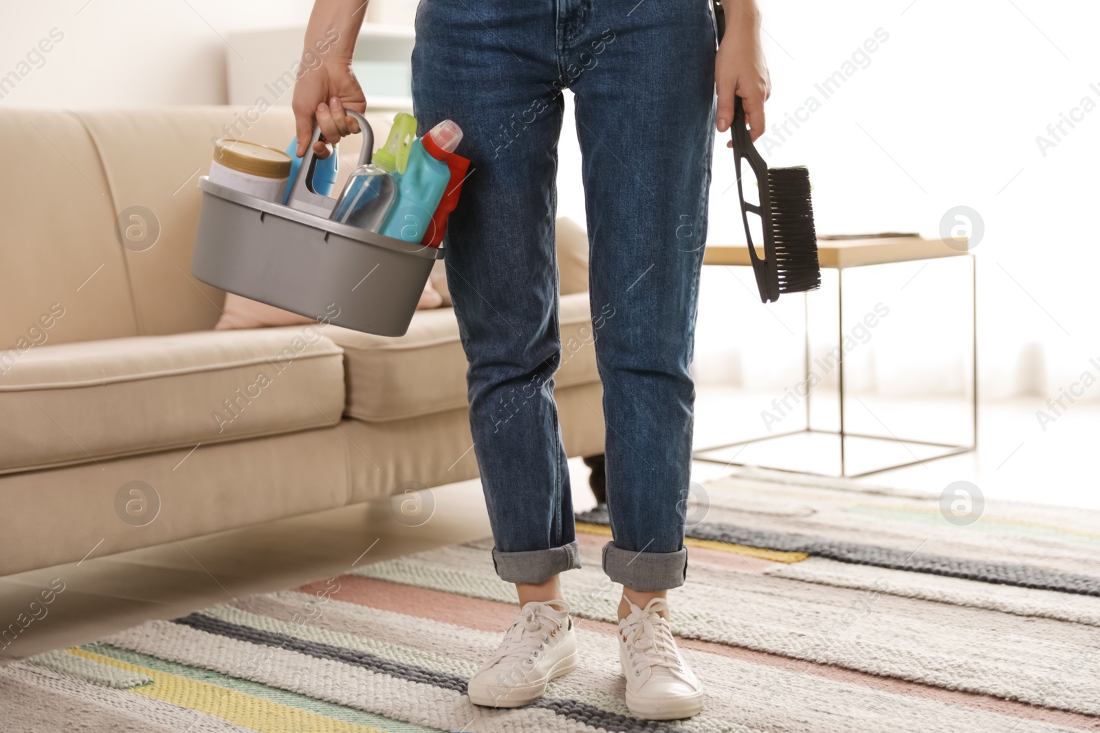 Photo of Woman with basket of professional cleaning products indoors, closeup