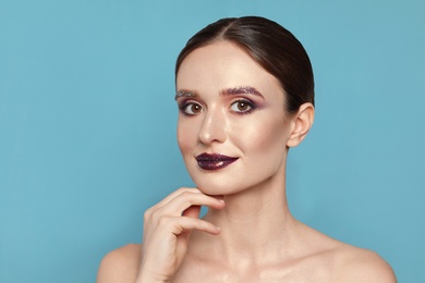 Photo of Beautiful young woman with glitter makeup on blue background