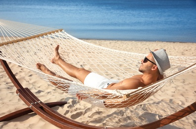 Young man relaxing in hammock on beach