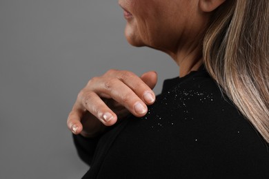 Photo of Woman brushing dandruff off her sweater on gray background, closeup. Space for text