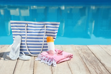 Photo of Beach accessories on wooden deck near outdoor swimming pool, space for text
