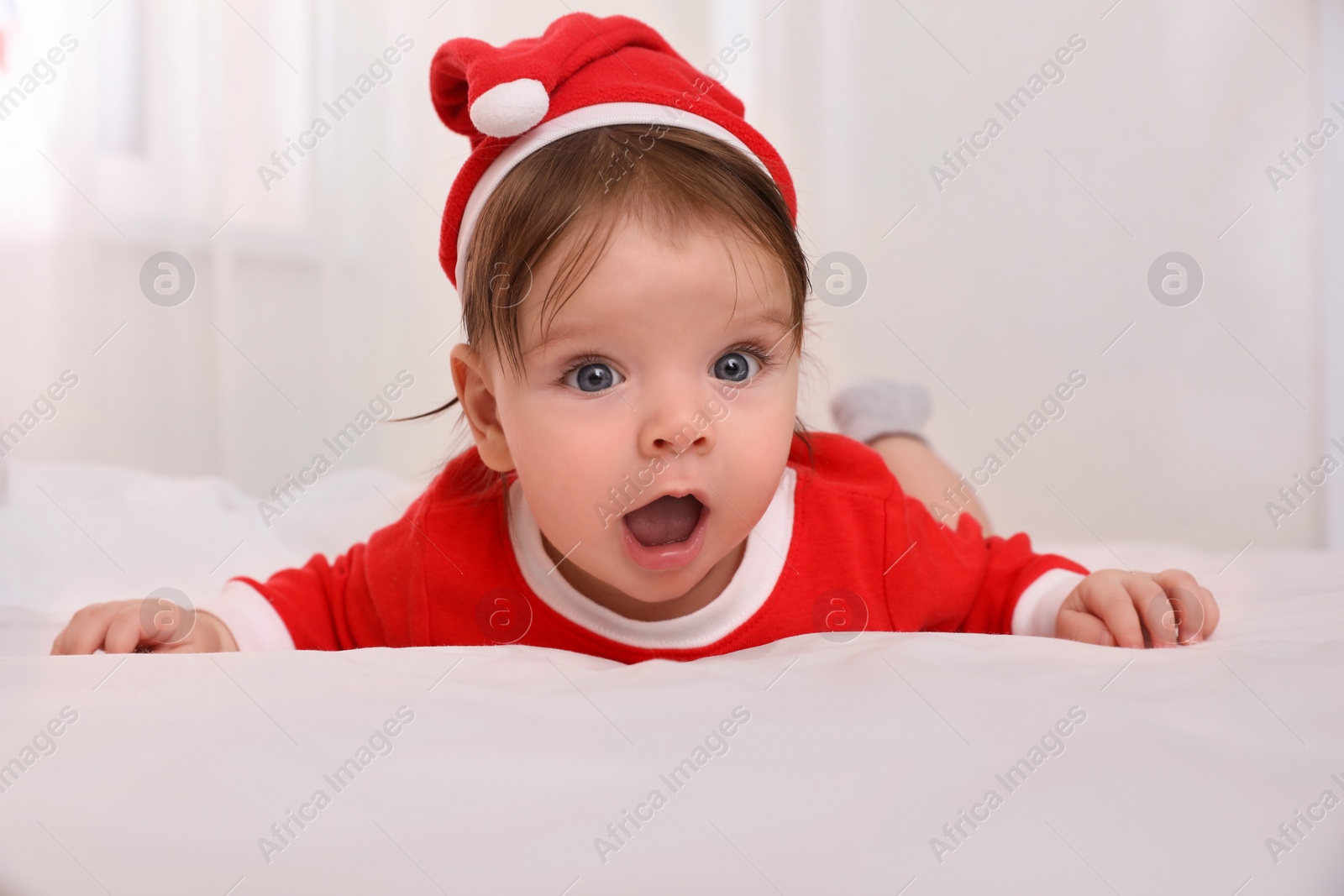 Photo of Cute baby wearing festive Christmas costume on bed