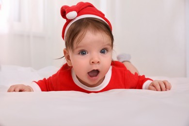 Photo of Cute baby wearing festive Christmas costume on bed
