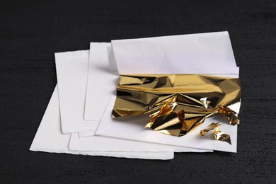 Photo of Edible gold leaf sheets on black table, closeup