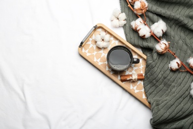 Photo of Flat lay composition with hot drink and warm plaid on white bedsheet, space for text