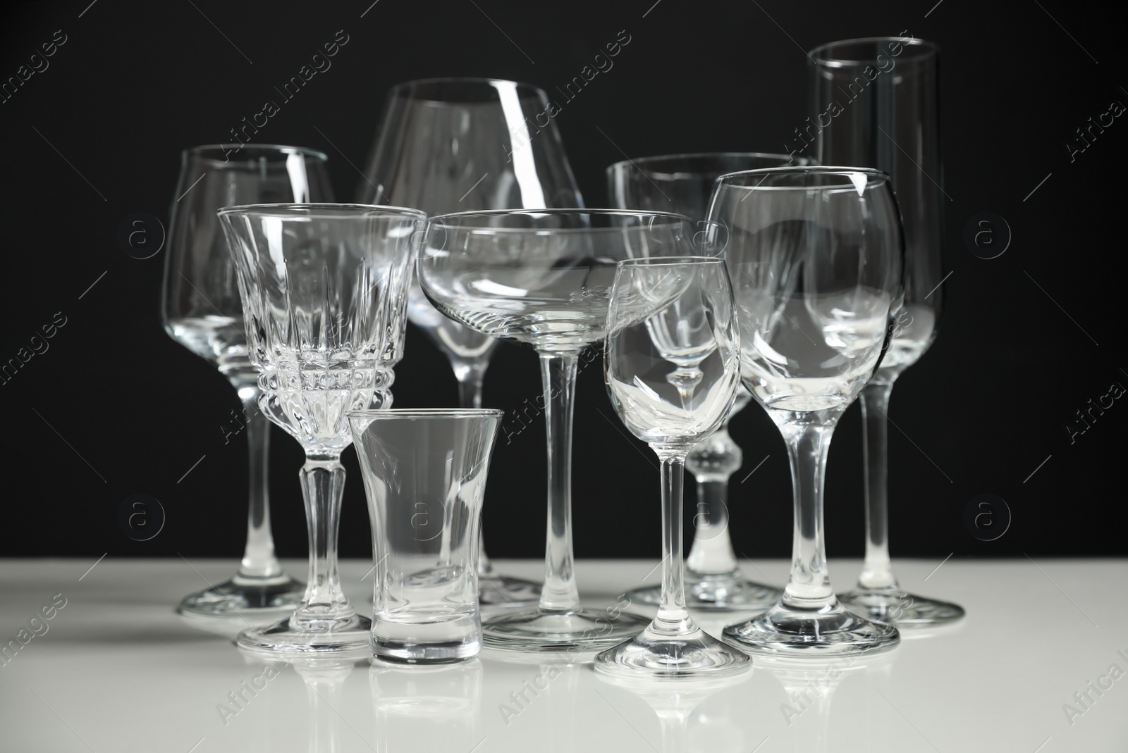 Photo of Set of bar glassware on white table against black background