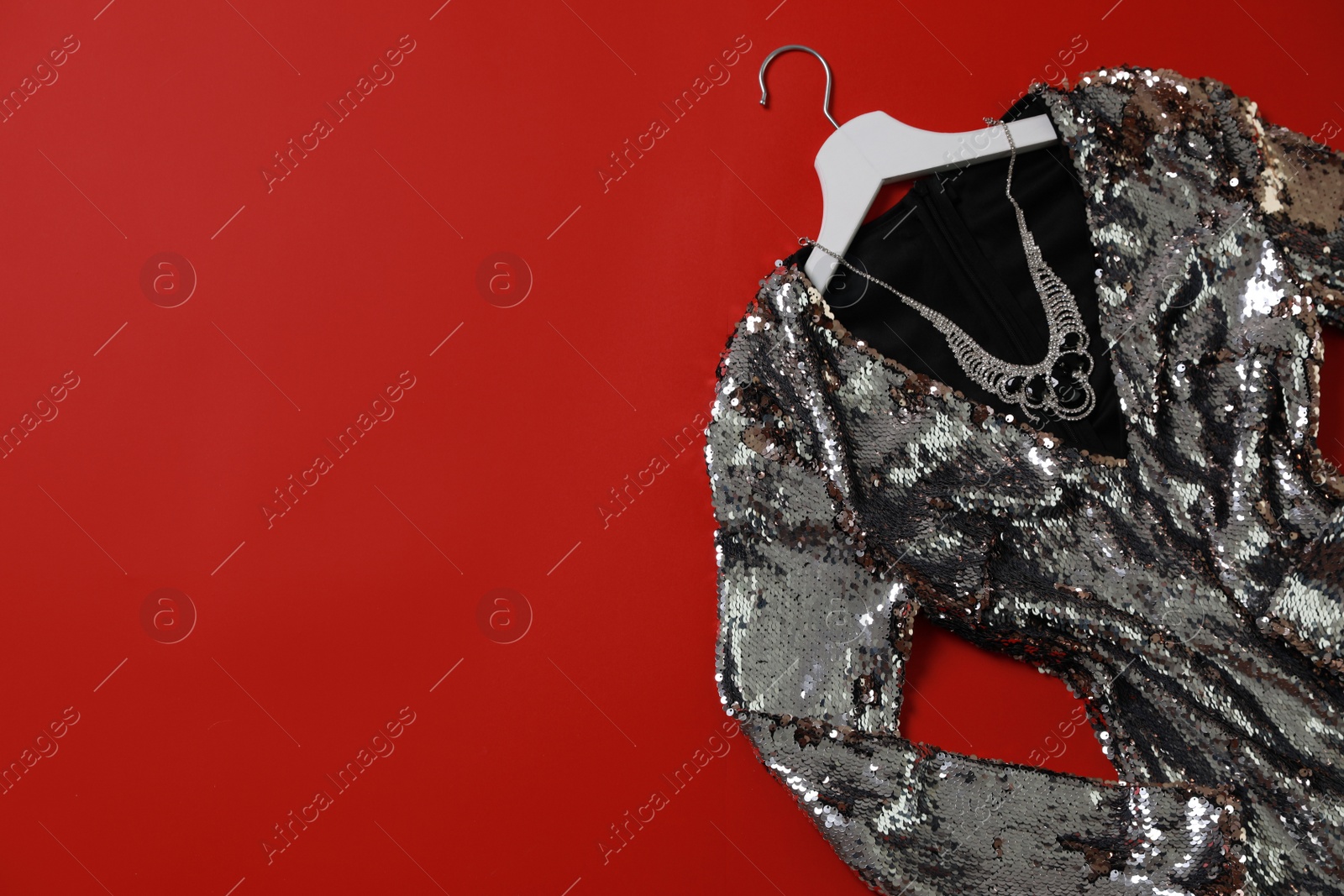 Photo of Beautiful dress and necklace on red background, flat lay with space for text. Rental clothing service