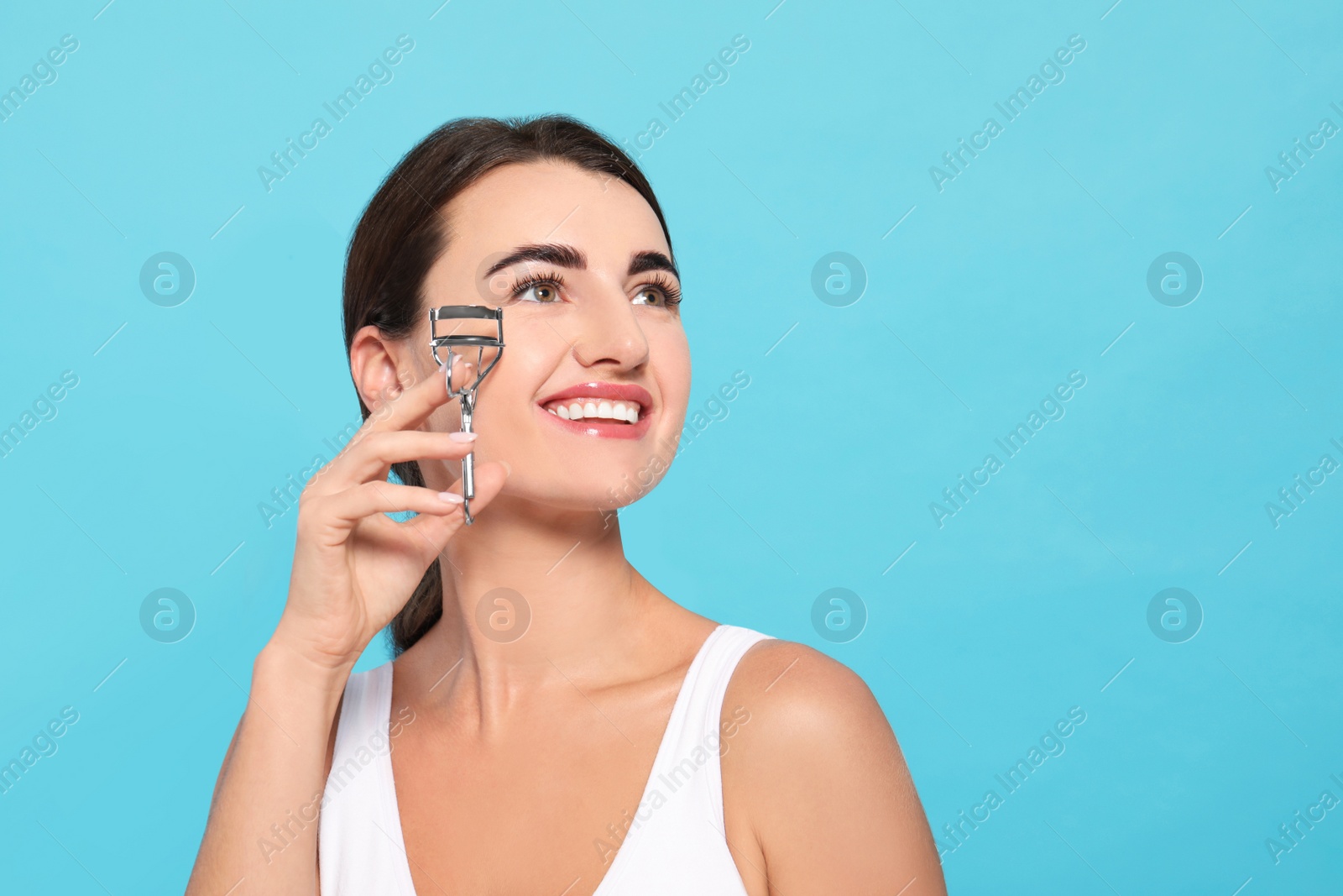 Photo of Woman with eyelash curler on turquoise background. Space for text