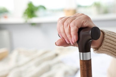 Photo of Elderly woman with walking cane indoors, closeup. Home care service