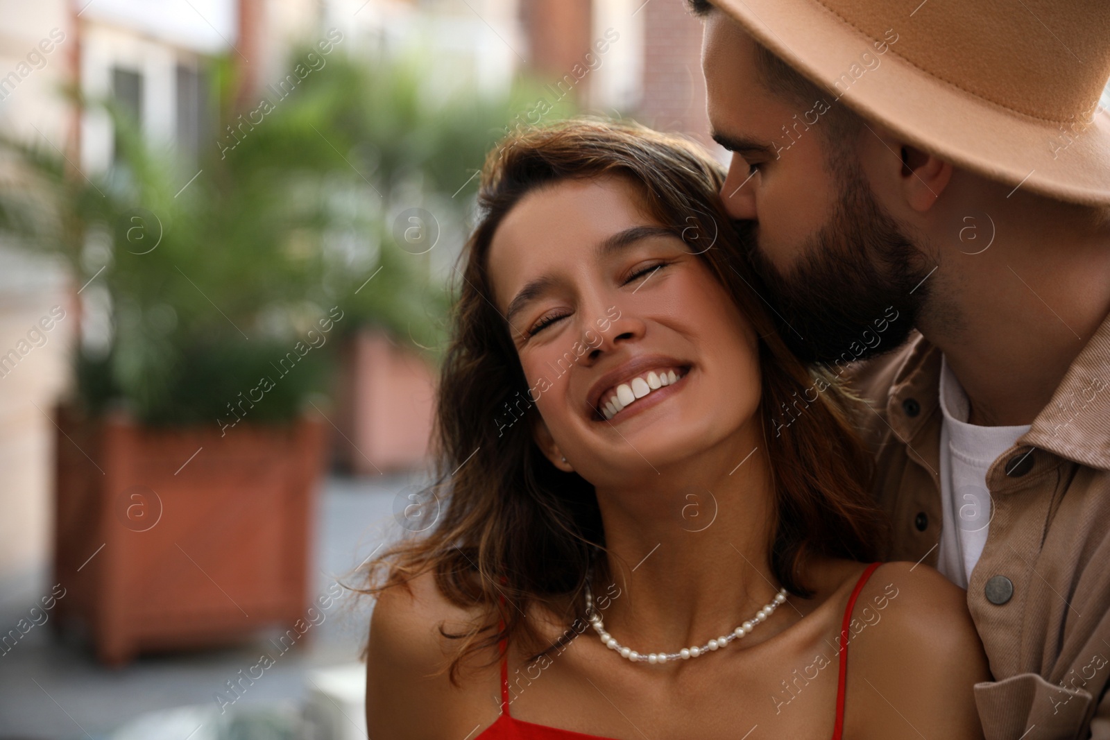 Photo of Handsome young man kissing his beautiful girlfriend on city street