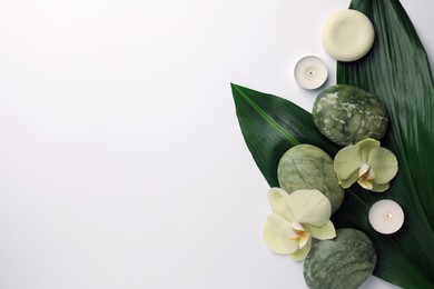 Flat lay composition with spa stones, solid shampoo bar and beautiful flowers on white table. Space for text