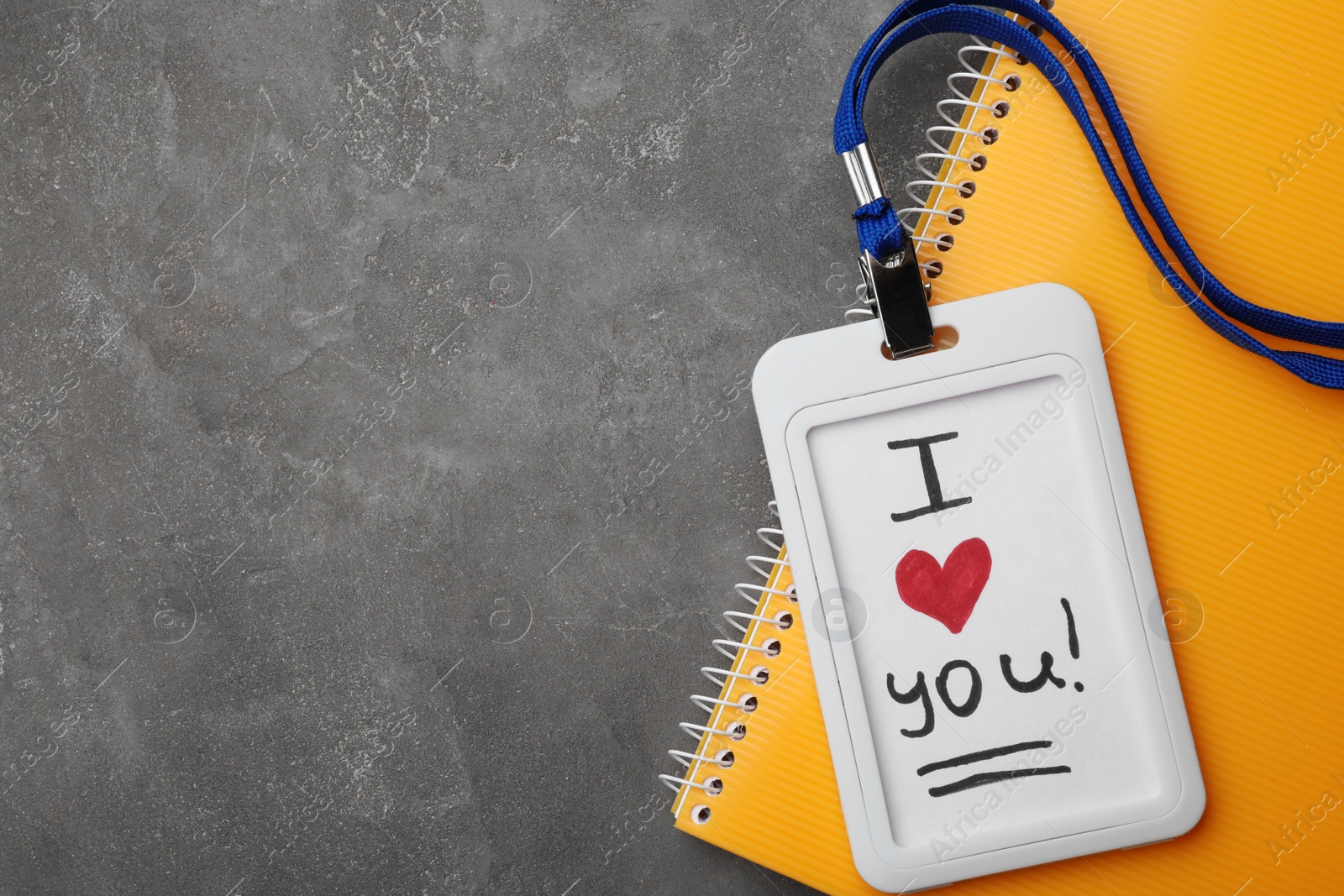 Photo of Badge with words I LOVE YOU and notebook on grey table, flat lay. Space for text