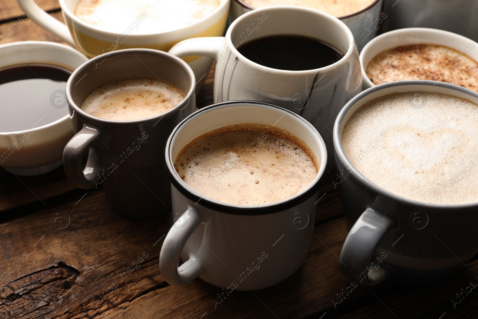 Photo of Many cups of different coffees on wooden table, closeup