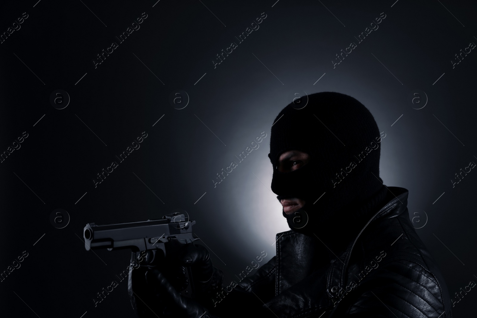 Photo of Man wearing knitted balaclava with gun on black background