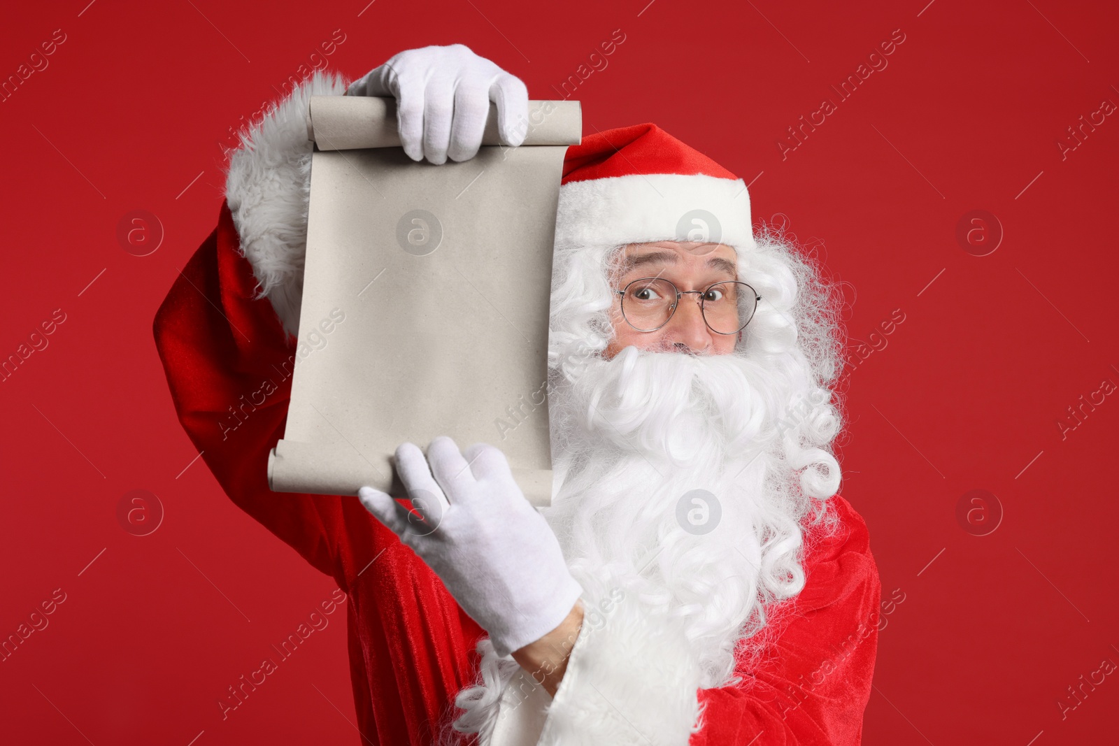 Photo of Merry Christmas. Santa Claus showing blank paper sheet on red background