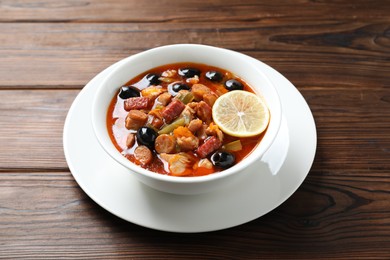 Meat solyanka soup with sausages, olives and vegetables on wooden table