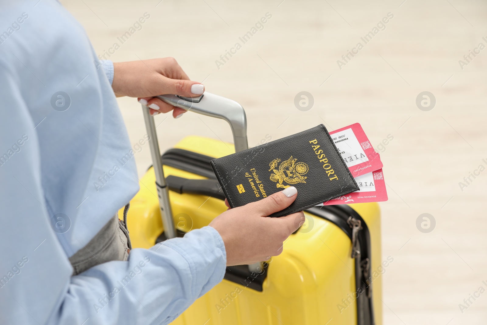 Photo of Woman with suitcase, passport and tickets on blurred background, closeup
