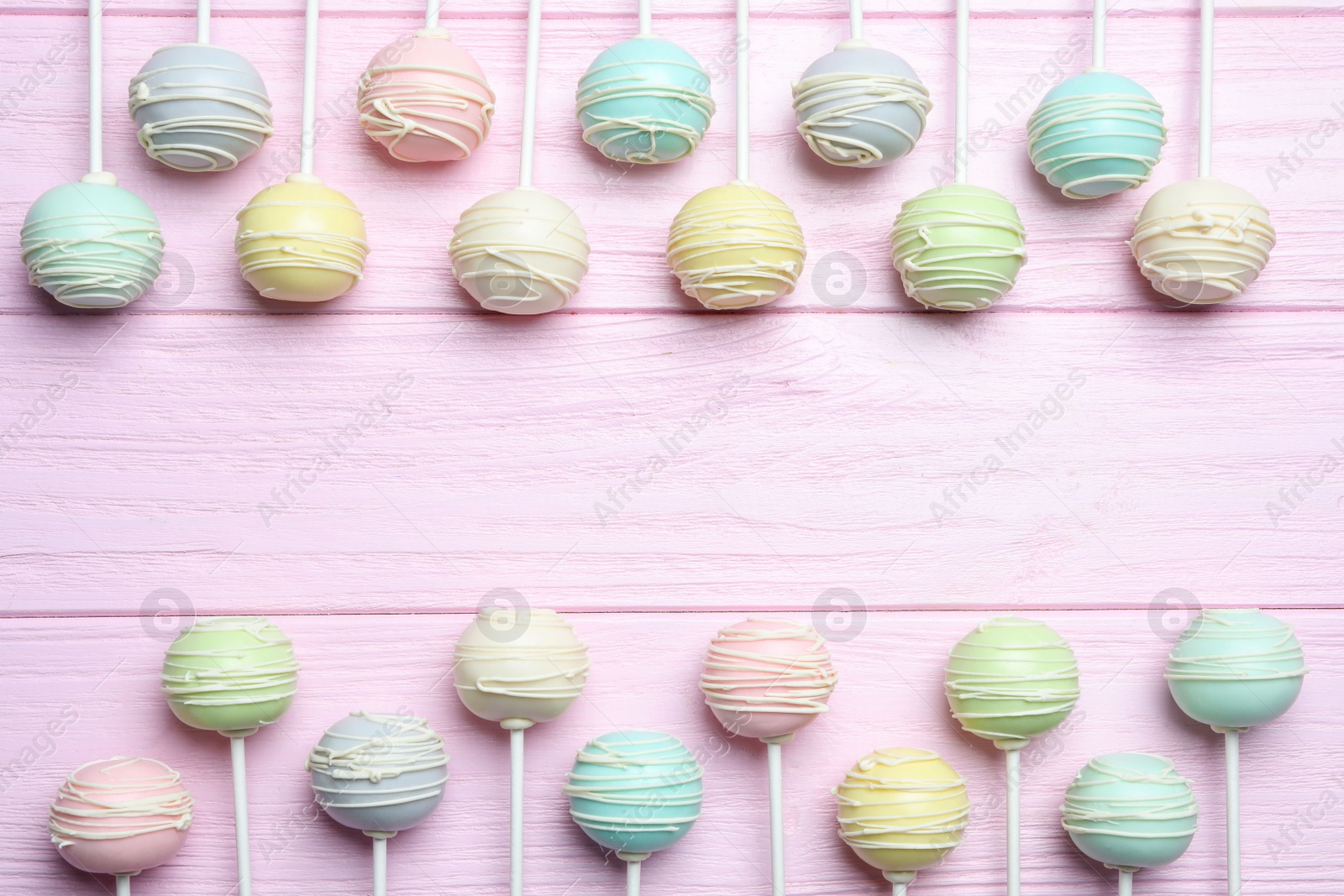 Photo of Frame made of sweet cake pops on pink wooden background, top view. Space for text