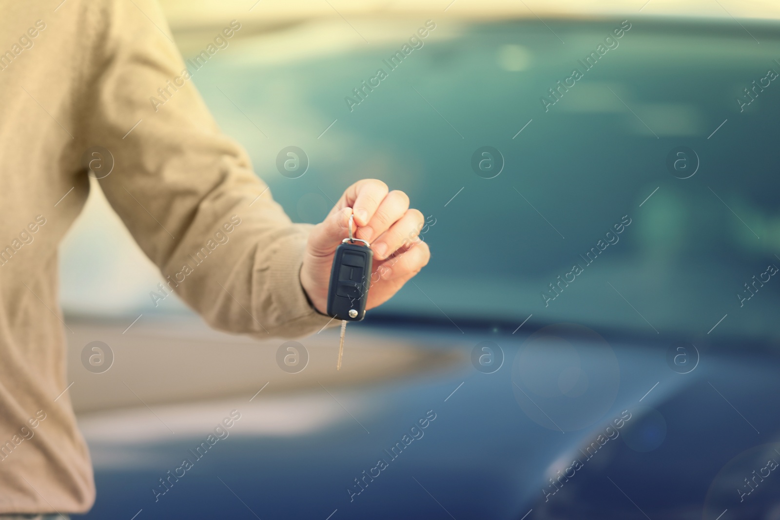 Image of Man holding key in modern auto dealership, closeup. Buying new car