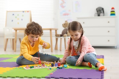 Cute little children playing with math game Fishing for Numbers on puzzle mat in kindergarten