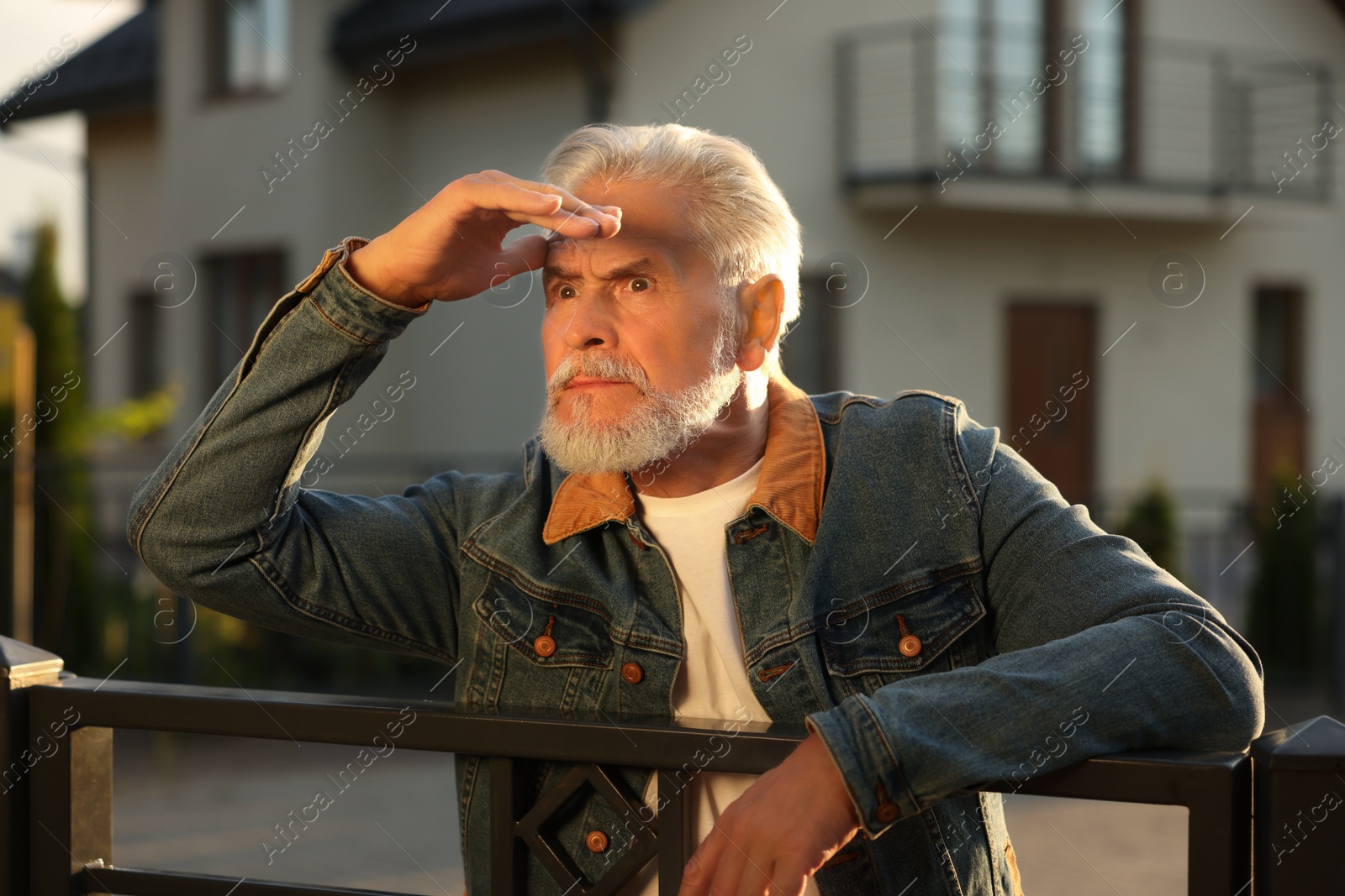 Photo of Concept of private life. Curious senior man spying on neighbours over fence outdoors