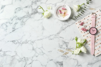 Flat lay composition with flowers, notebook and wristwatch on white marble background, space for text