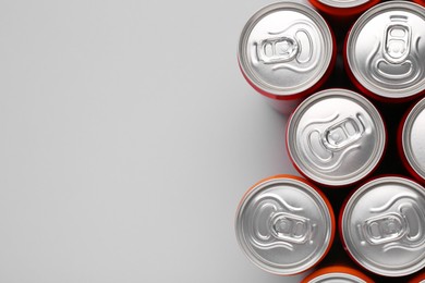 Photo of Energy drink in cans on grey background, top view. Space for text