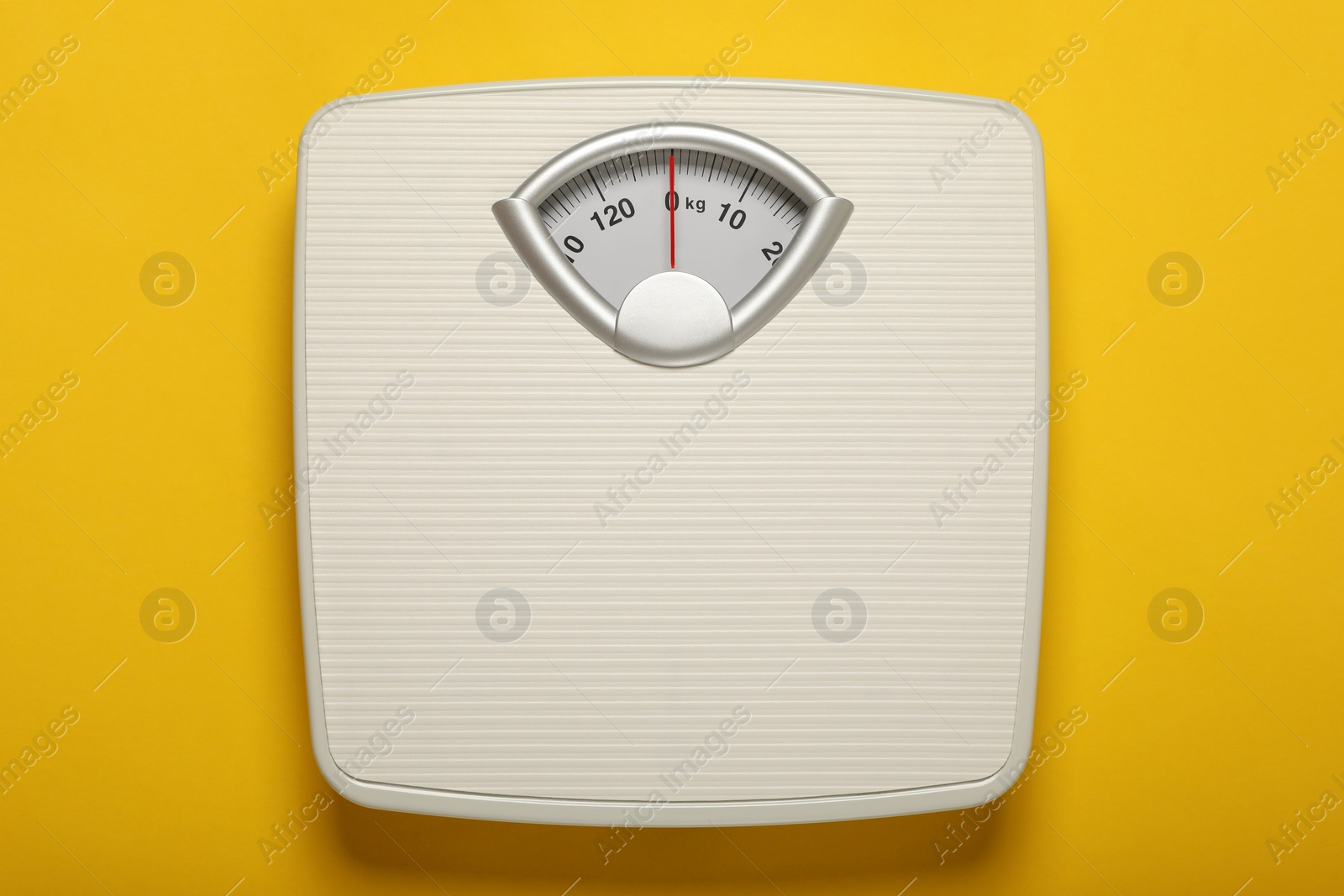 Photo of Weigh scales on yellow background, top view. Overweight concept
