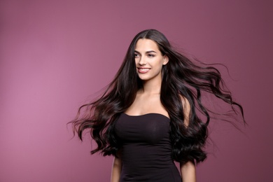 Portrait of beautiful model with gorgeous curly hair on color background