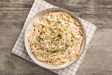 Photo of Bowl of delicious pasta with mushroom sauce and parmesan cheese on wooden table, top view