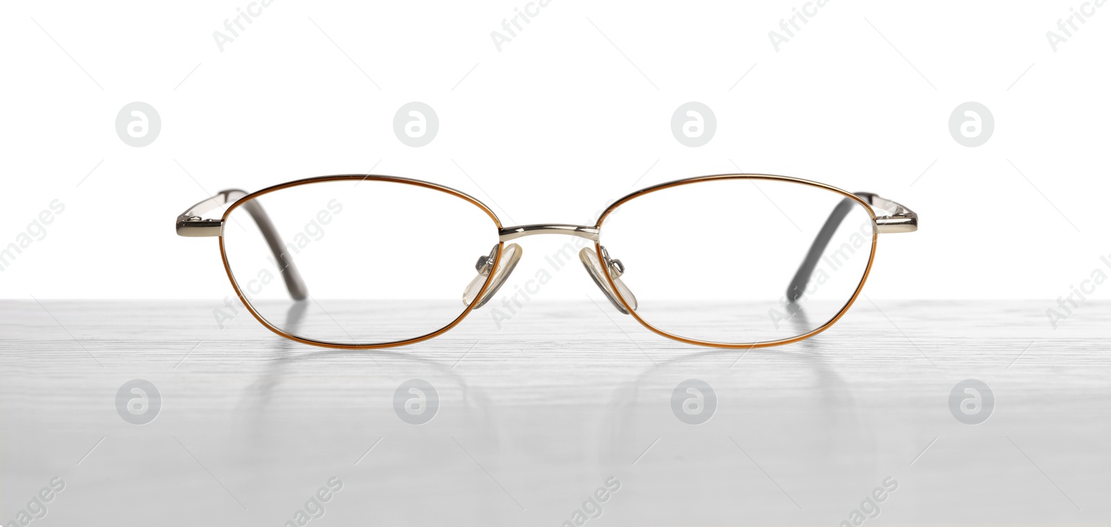 Photo of Stylish glasses with metal frame on table against white background