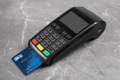 Photo of Modern payment terminal with credit card on grey background