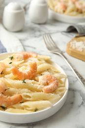 Delicious pasta with shrimps served on white marble table