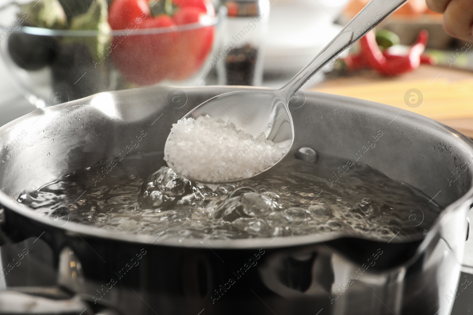 Photo of Salting boiling water in pot on stove, closeup