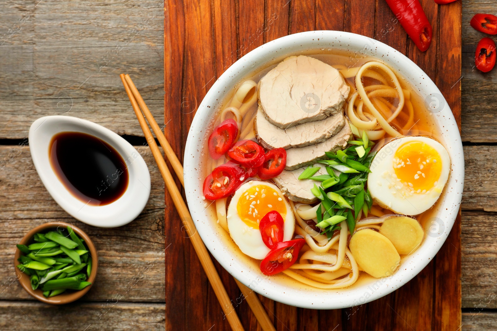 Photo of Delicious ramen in bowl served on wooden table, flat lay. Noodle soup