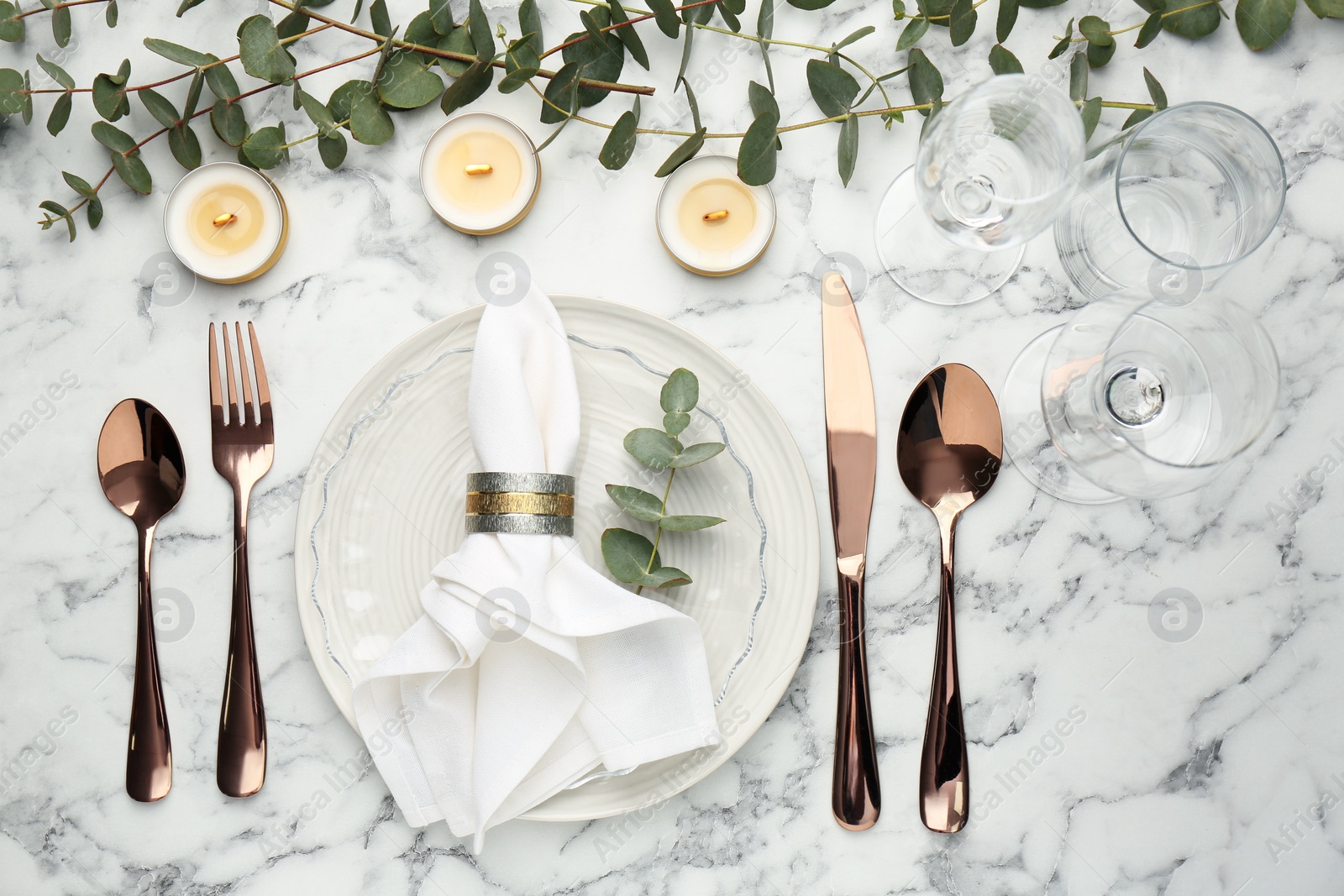 Photo of Beautiful place setting with candles and eucalyptus on white marble table, flat lay