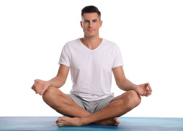 Photo of Handsome man meditating on yoga mat against white background